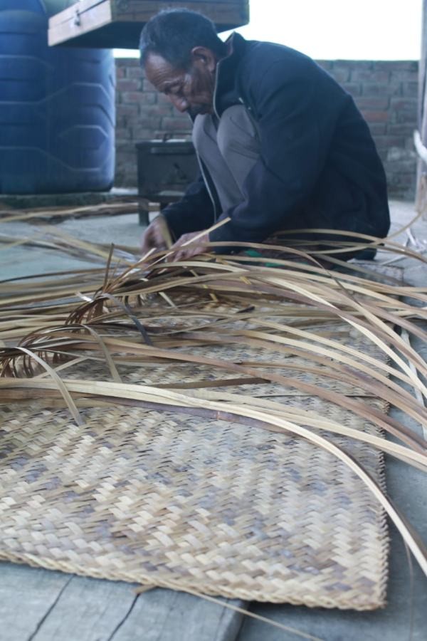 Neikehie weaves a bamboo mat by criss-crossing bamboo slivers (inset) at his home in Phesama village under Kohima district. (Morung Photo)